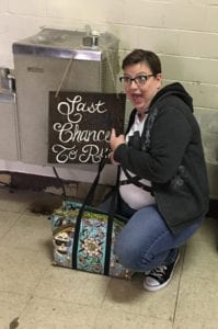 Jen posing by a sign in Poasttown Elementary 